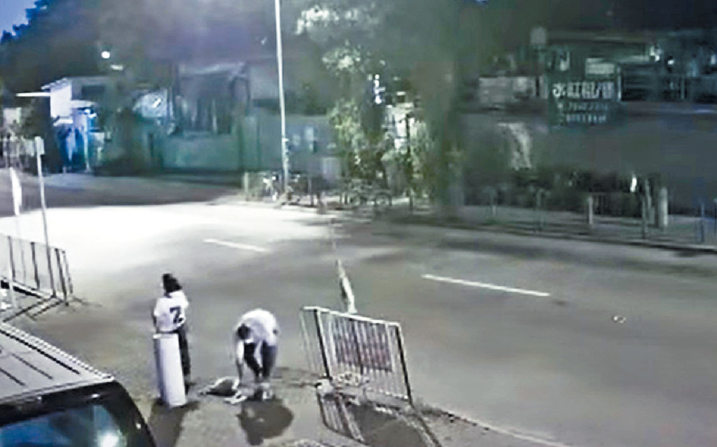 ■一對男女將狗屍搬回路邊,避免牠再被車輛輾過。 ■一對男女將狗屍搬回路邊,避免牠再被車輛輾過。