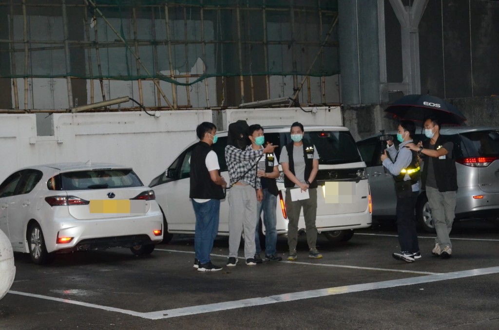 警方押解其中一名疑犯到涉事地點重組案情。