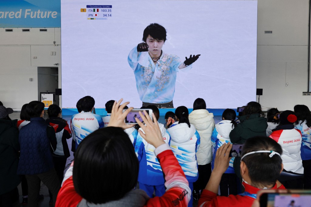 大批冬奧義工在大電視前觀看，關注花滑王子的表現。REUTERS