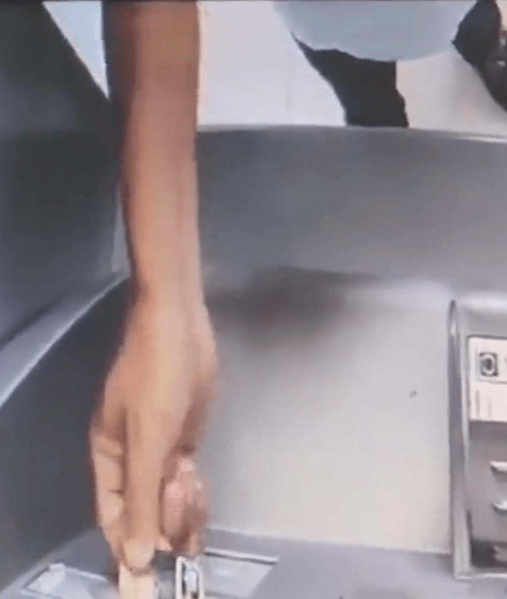 闭路电视拍下男子将一叠「阴司纸」放入自动柜员机后，在旁边正常的ATM上查看馀额。