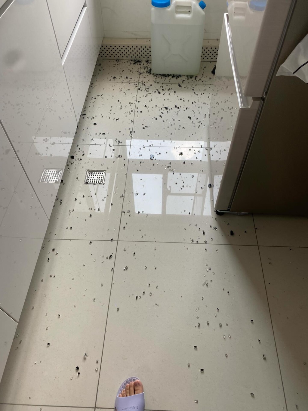玻璃碎片密密麻麻散落於灶台與地面，現場一片狼藉。