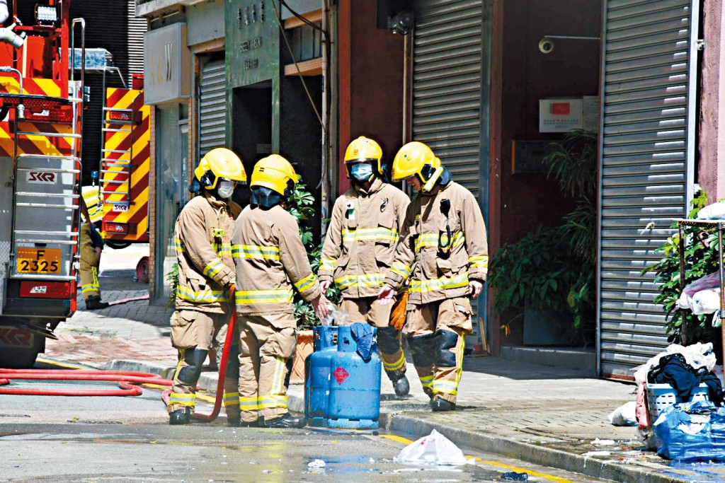 消防員在洗衣店內搬出肇事的石油氣樽檢查。