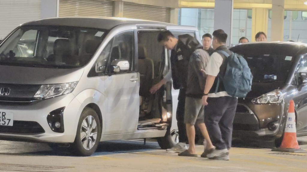 疑犯被黑布蒙頭，雙手扣上金銬被帶離警署。黃文威攝