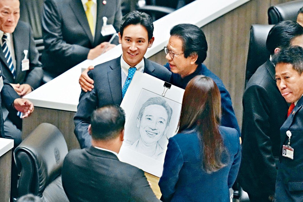 前进党党魁皮塔（左）被宪法法庭暂停众议员职务，他离开议事厅前，展示为泰党议员赠送他的肖像。