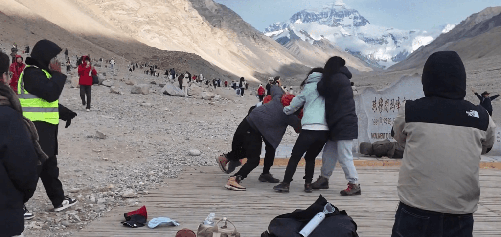 珠穆朗瑪峰一對情侶在紀念碑前打大出手，灰衫男子將燈衫男撲倒。