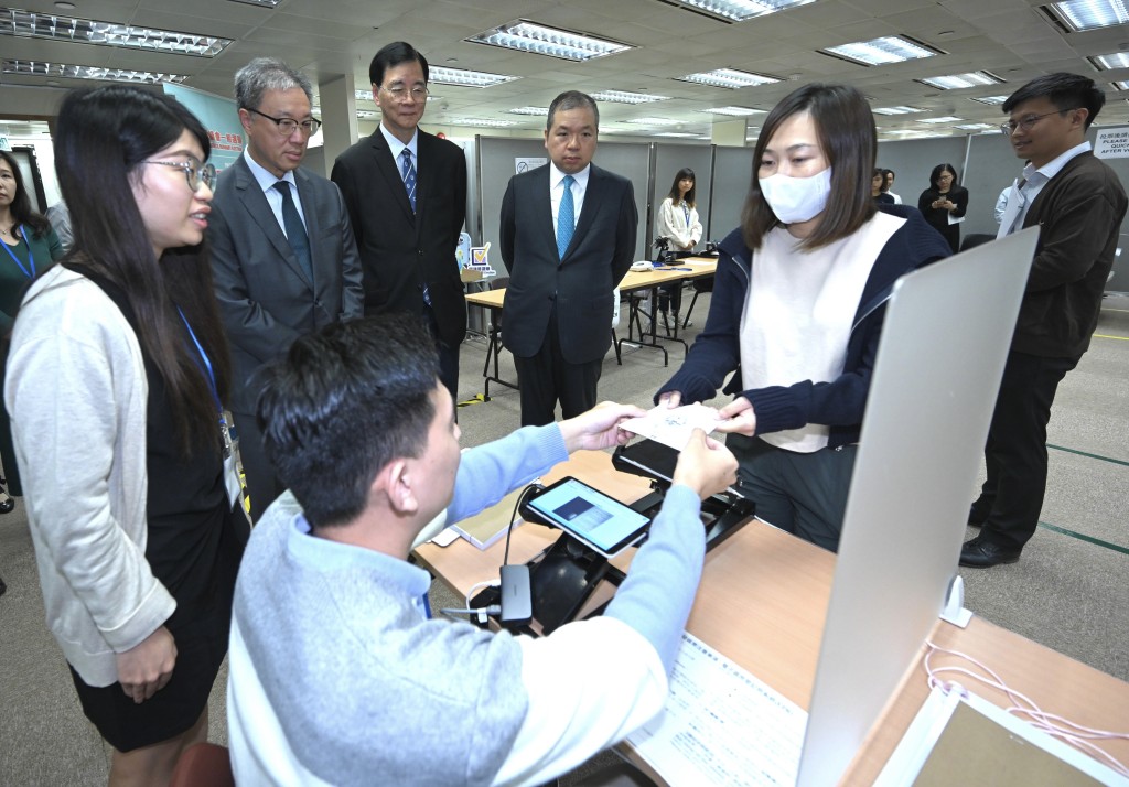 陆启康（左二）、石丹理教授（左三）及文本立（左四）听取选举事务处工作人员示范使用电子选民登记册系统发出选票的程序。政府新闻处图片
