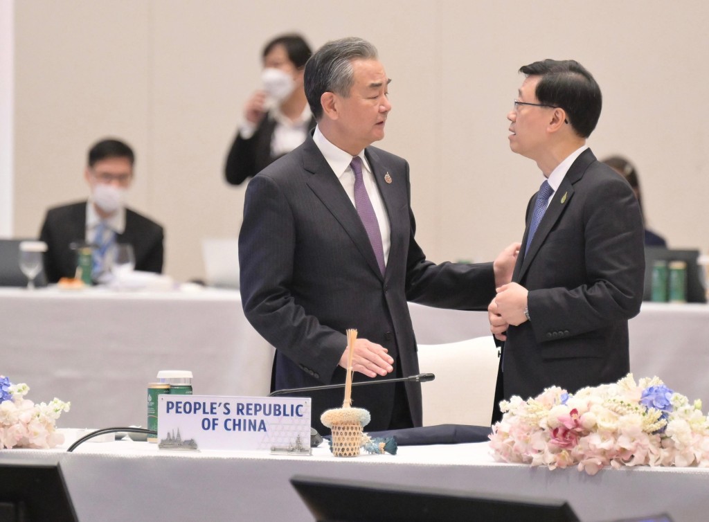 李家超在去年APEC會議中，與外交部部長王毅（左）對話。政府新聞處圖片