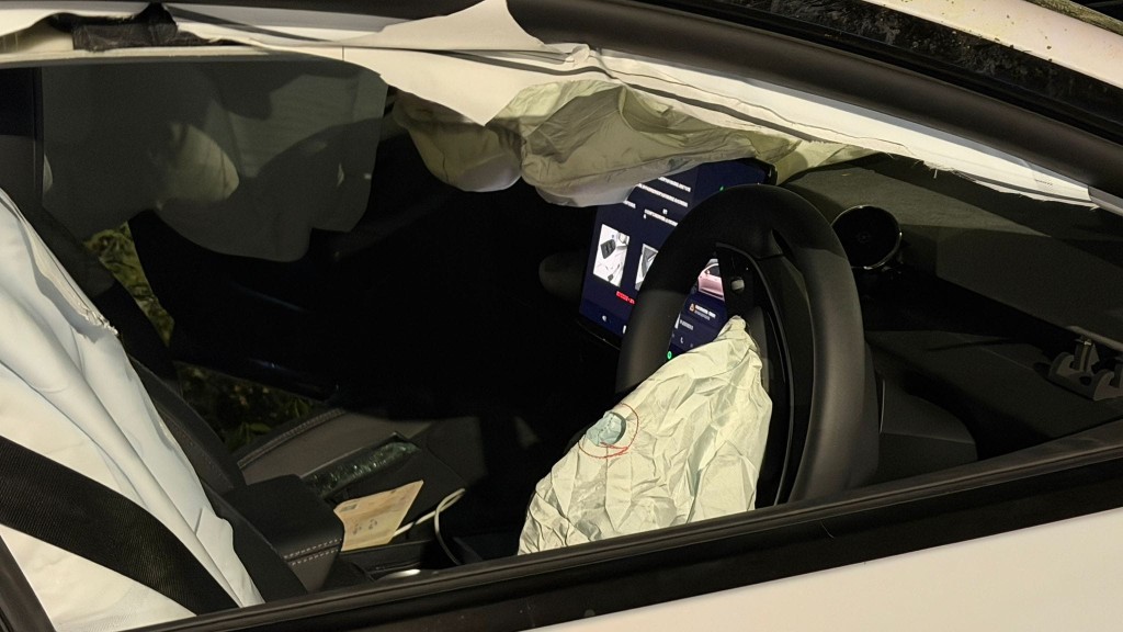 Tesla擱在草叢上，車頭嚴重損毀，機件明顯外露，車架扭曲，儼如廢鐵。蔡楚輝攝