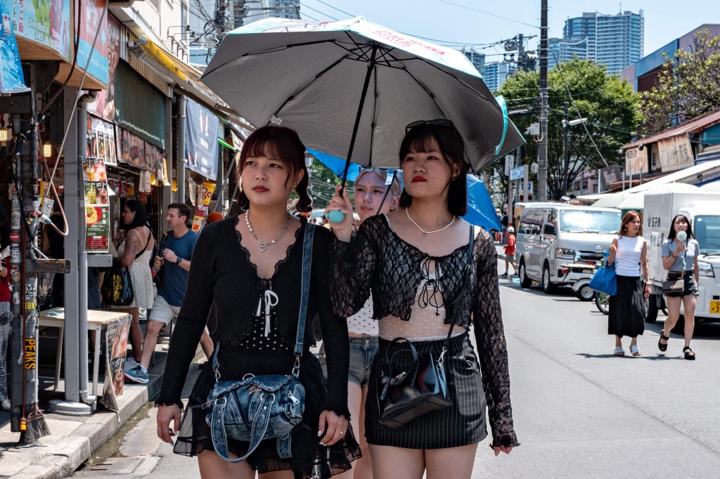 東京都測得36.1度高溫，行人都撐傘遮擋陽光。法新社