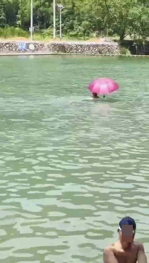 有泳客撑伞畅泳。网上截图
