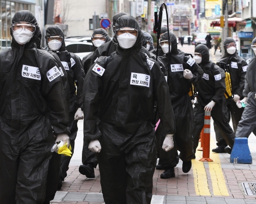 在大邱市街頭，有穿著保護衣的南韓軍方人員噴灑消毒劑。 AP圖