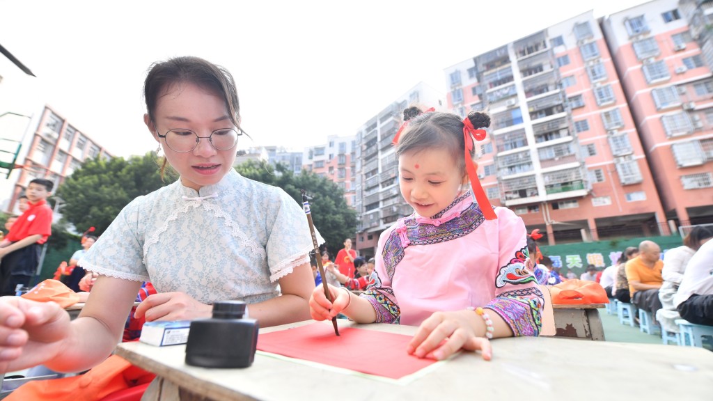小學生學習中國文化，在開筆禮儀式上用毛筆寫「人」字。 新華社