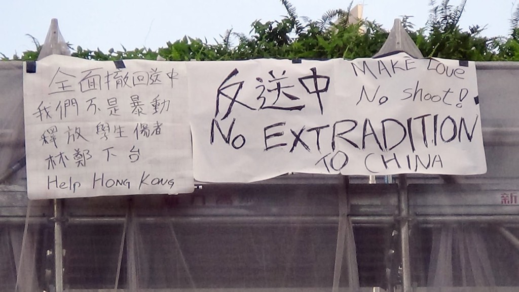 一名男子在金鐘太古廣場的平台掛上反對修例的橫額。