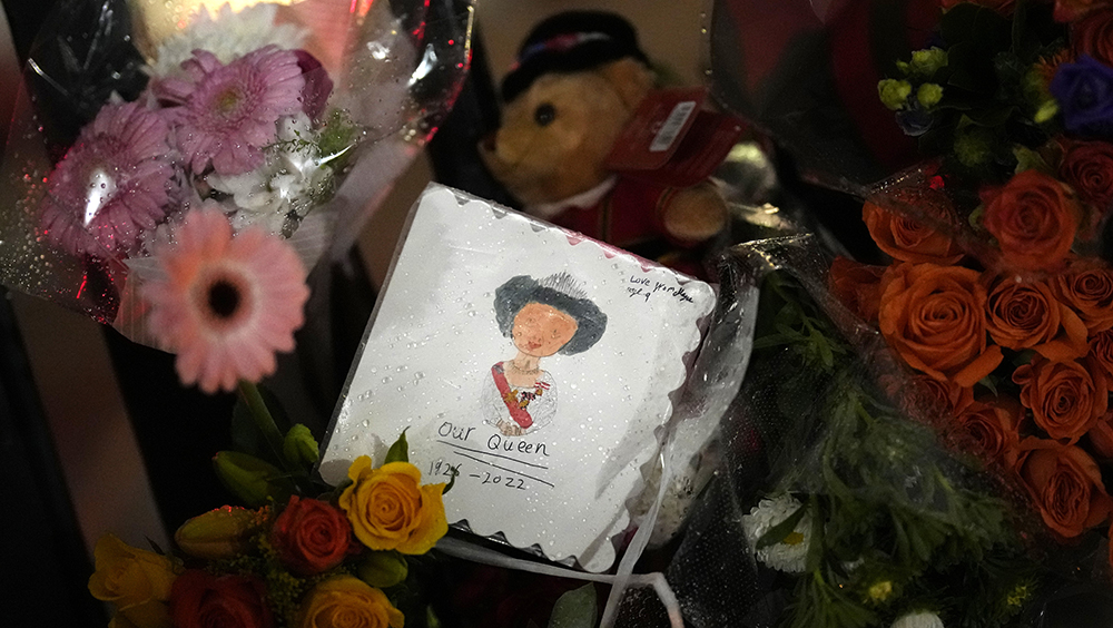 民众绘画放在伦敦白金汉宫外的鲜花旁，悼念英女皇伊利沙伯二世去世。AP