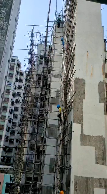 工人從樓頂將竹枝接力遞往樓下。