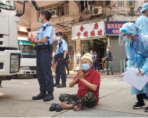 男子在炮台街近寧波街,坐在馬路上替區內受疫情影響的居民祈福。
