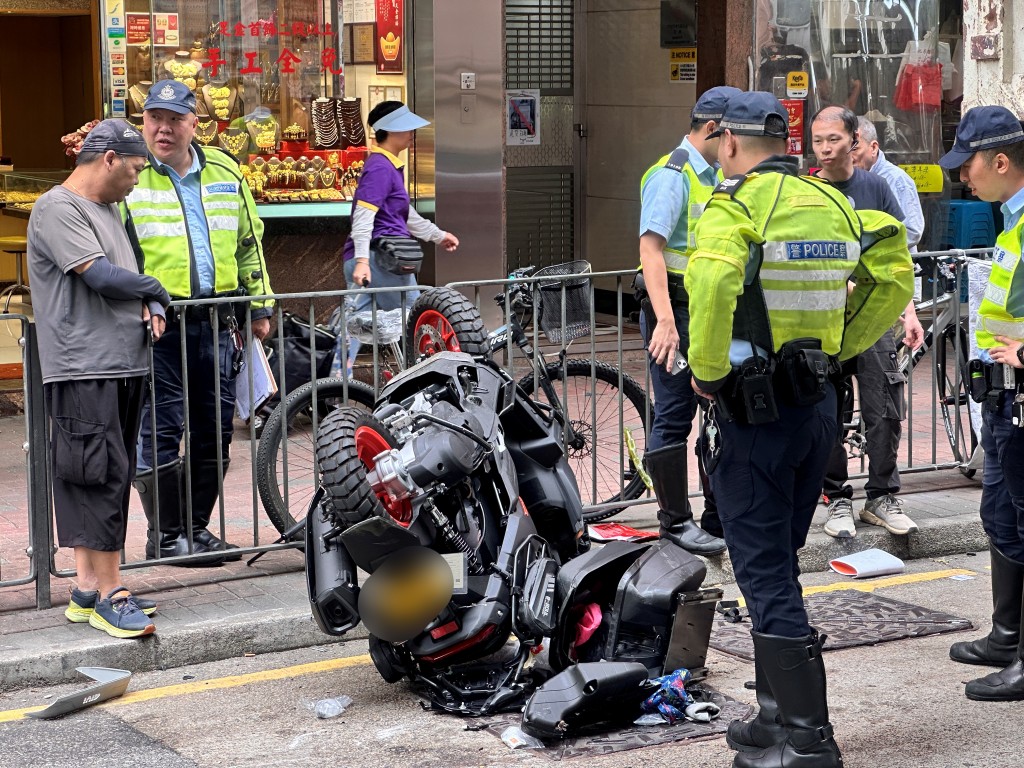 電單車撞車後整架倒轉，車頭撞毀，傷者友人（圖左）到場善後。梁國峰攝