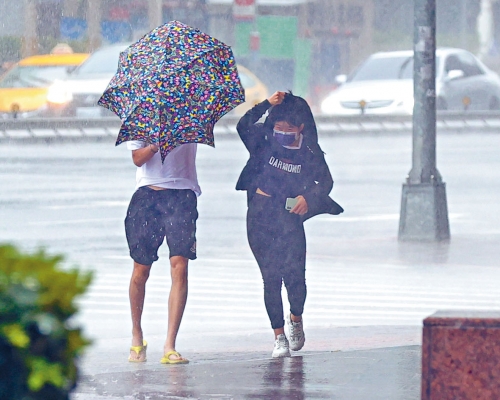 ■颱風來襲,台灣民眾冒着風雨出門。