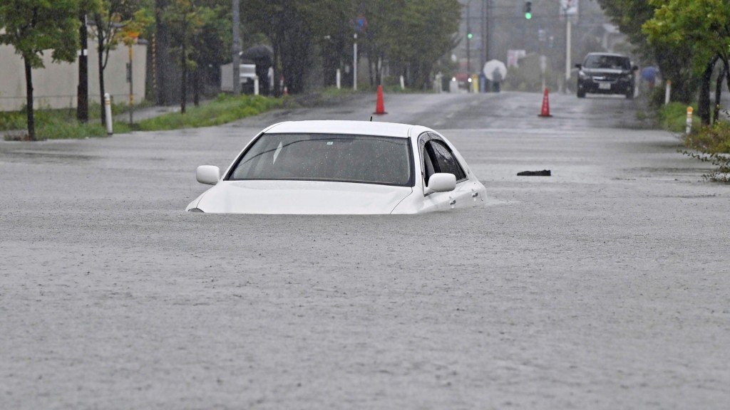 秋田市道路水浸一輛汽車駛過幾乎被淹沒。美聯社