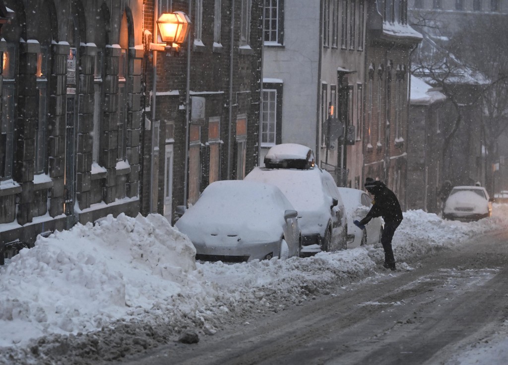 停泊在路边的汽车盖上厚厚积雪。AP