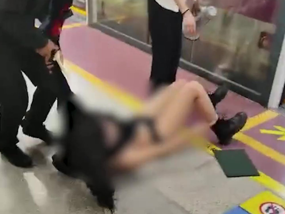 女乘客被保安強行拉下車廂,衣服幾乎被扯脫。
