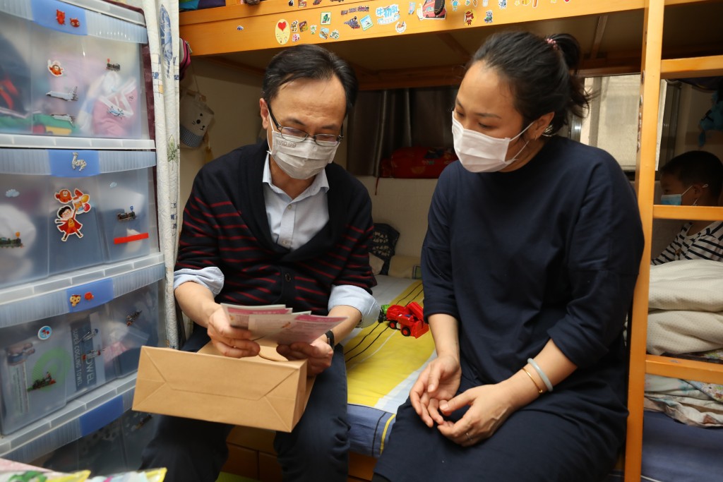 聶德權(左)向深水埗區的新來港家庭派發防疫宣傳單張,並向他們講述防疫健康資訊。 政府圖片