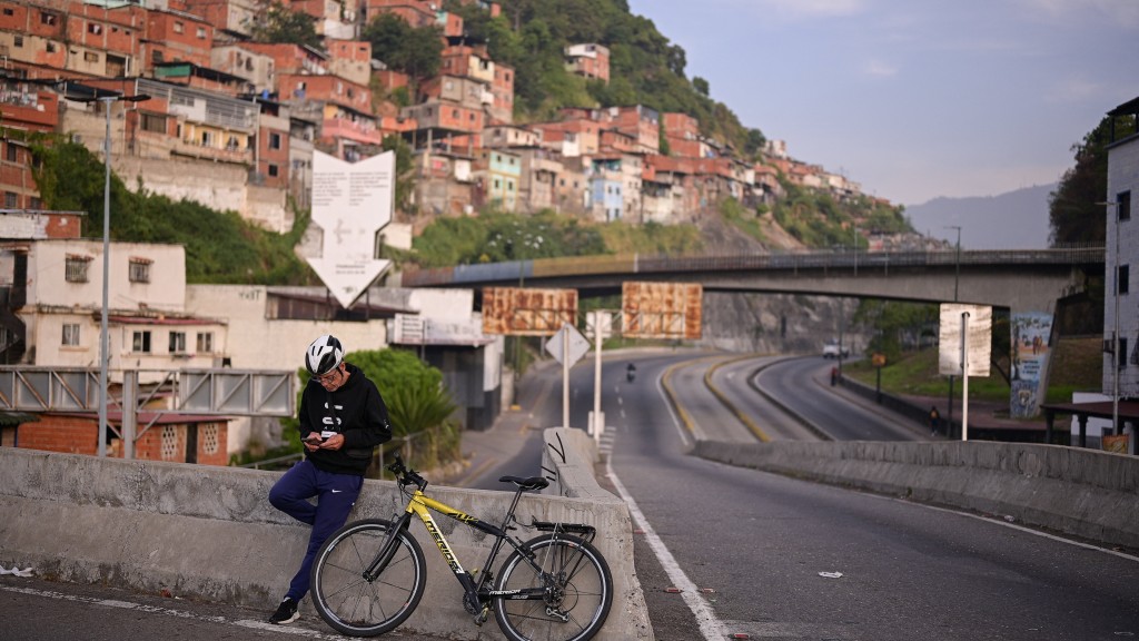 美國空襲委內瑞拉後，加拉加斯民眾停在路邊看手機。 路透社
