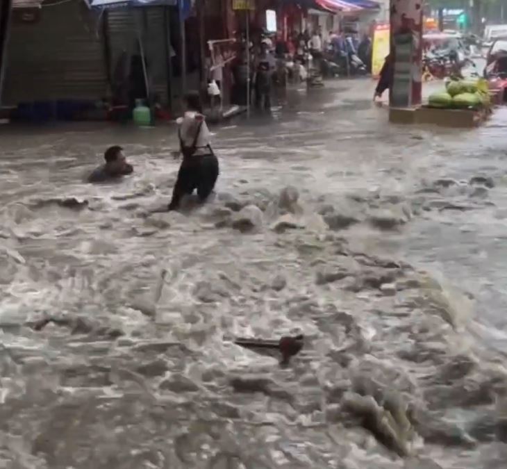 陕西长安区韦曲老街积水严重，有人拼命浸在积水中，企图保住被冲走的财物。