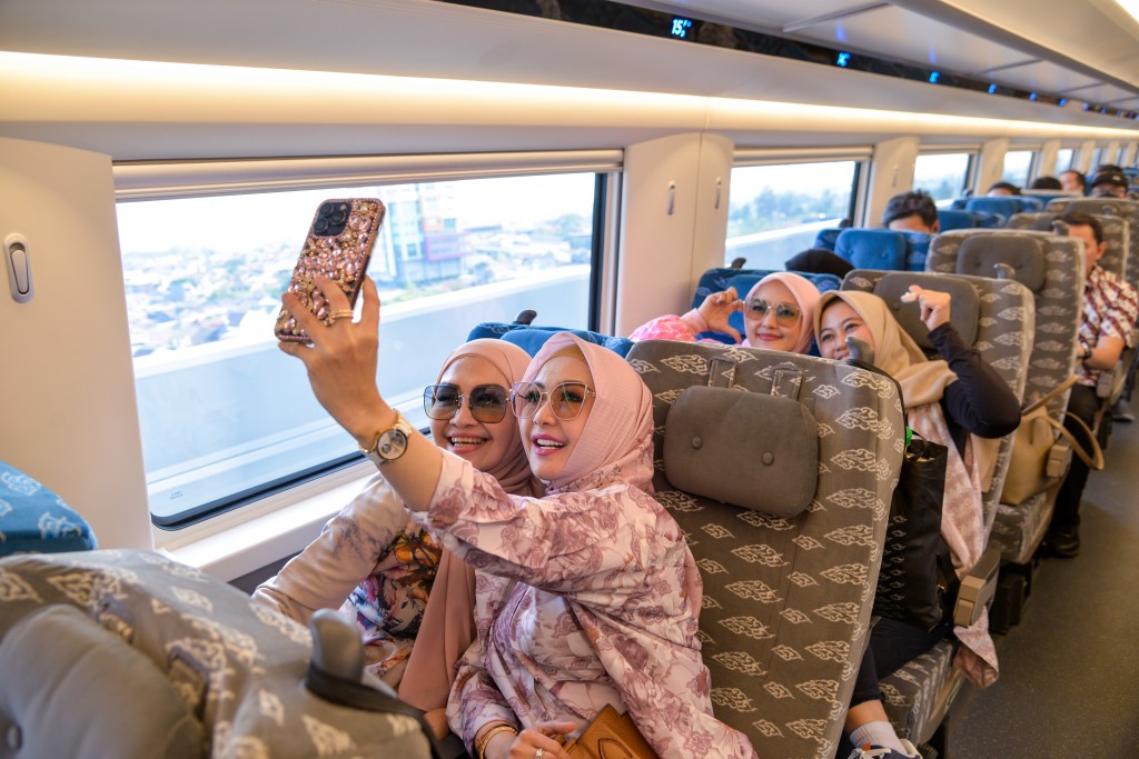 乘客在行驶中的雅万高铁高速动车组列车车厢内拍照。 新华社
