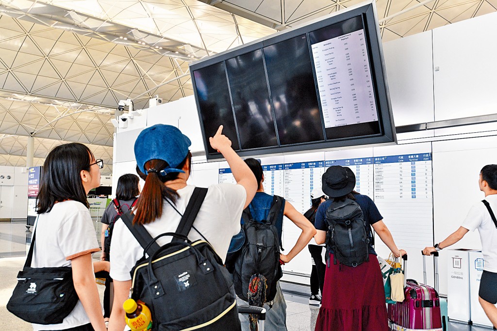機場電腦系統故障期間，旅客查看人手更新航班情況。