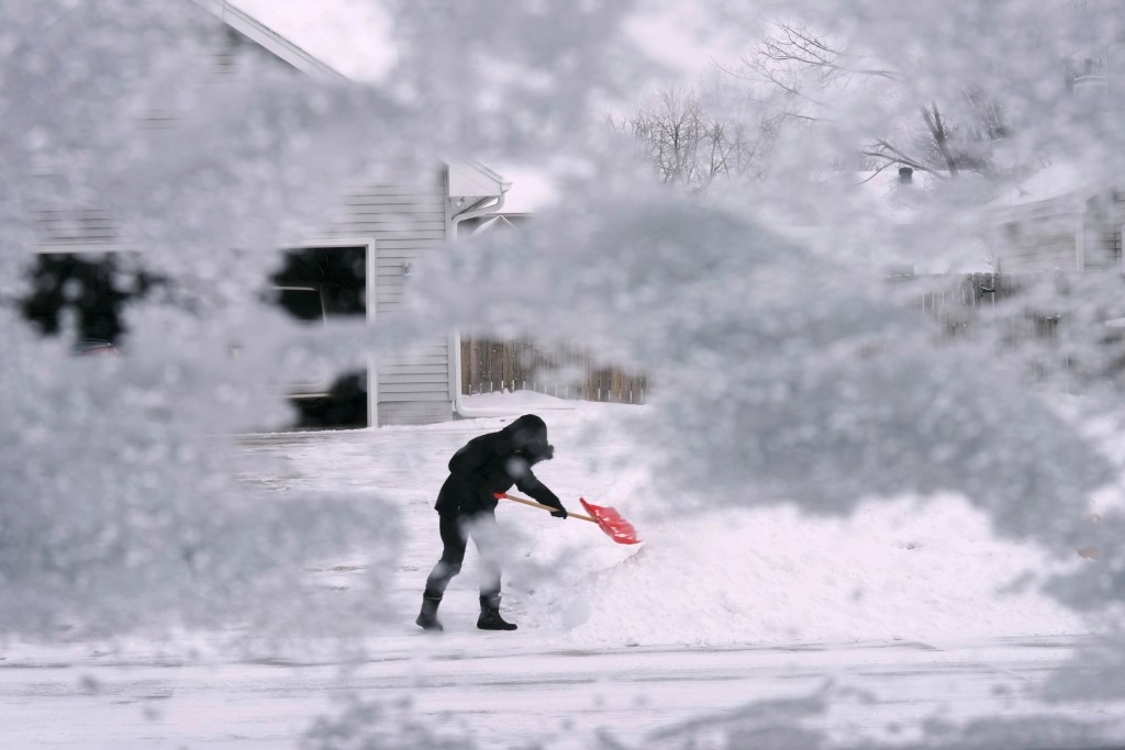 在爱荷华州厄本代尔，一名当地居民正在铲掉车道尽头的积雪。AP