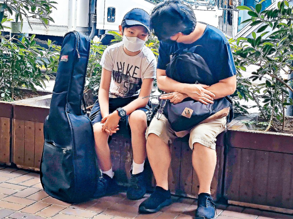 鍾先生（右）發現男孩Angus（左）在灣仔鵝頸橋底彈結他賣藝籌募學費，被其堅持夢想的精神感動。