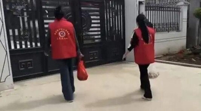 社区工作人员手持慰问物资（鸡蛋和鱼）。逐浪新闻