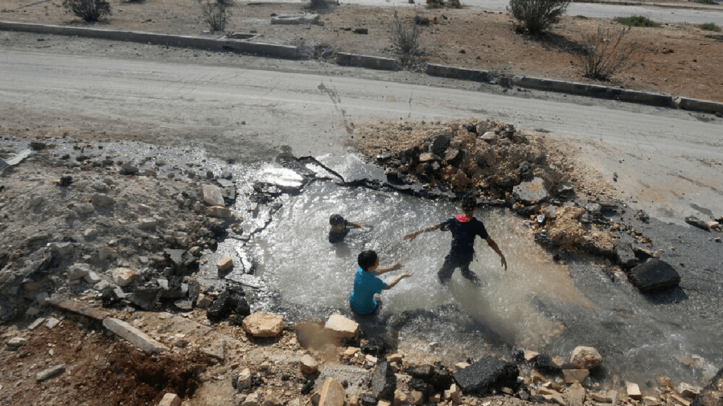 敘利亞兒童利用炸彈坑作泳池，苦中作樂。（路透社）