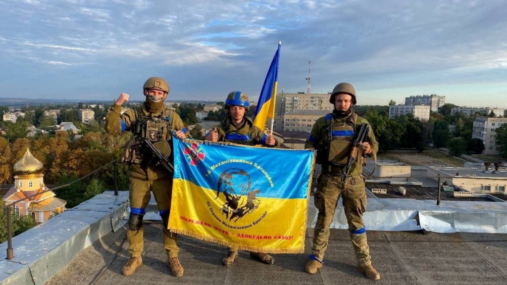 烏克蘭士兵在庫皮揚斯克的一個屋頂上舉起旗幟。REUTERS