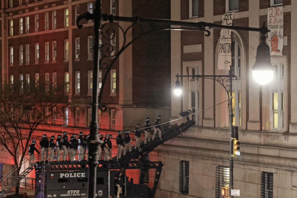 数十名戴着头盔和盔甲的纽约市警察周三凌晨用云梯闯入哥伦比亚大学一座学术大楼，将占据大楼的挺巴示威者拘捕和驱逐。 路透社