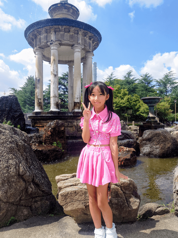 平田琉七在公園噴水池前比出招牌「V」手勢留影。