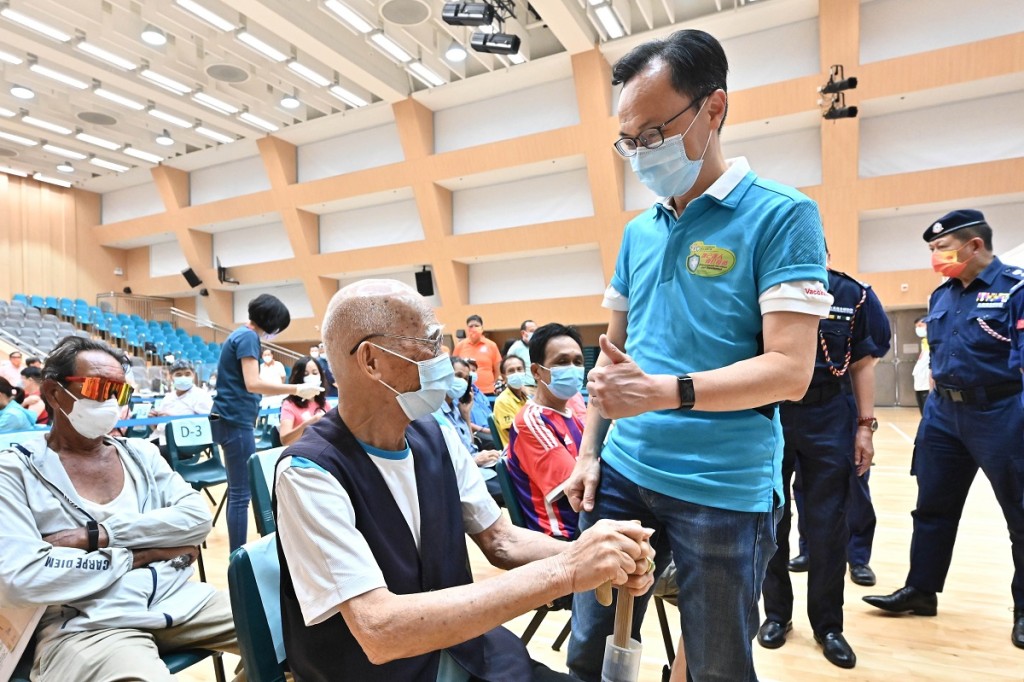 聶德權(前排右)在西貢賽馬會大會堂與一名91歲長者(前排左)交談。政府新聞處