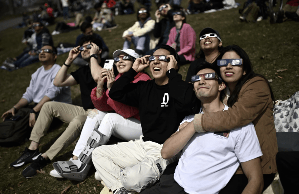 安大略省金斯顿，人们戴着日食眼镜观察日全食的部分阶段。美联社