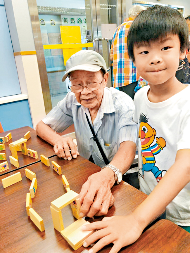 Alice的兒子與外公一起玩積木遊戲。