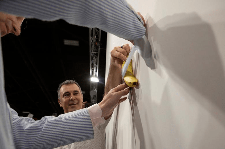 工作人员用银色封箱胶带将香蕉贴在展场的墙上，最终竟以高价卖出。路透