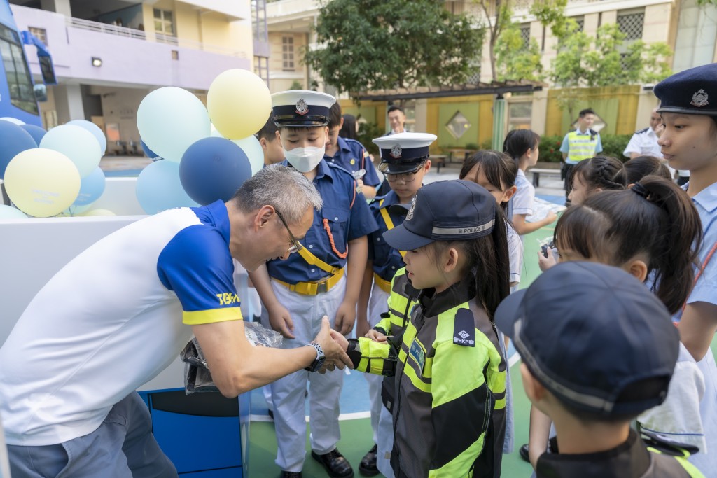 交通總部總警司梁珣與一眾交通安全隊小學隊員互動。