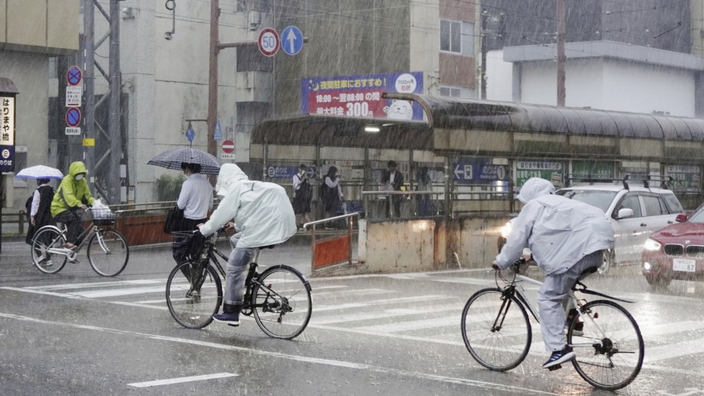 台风玛娃（Mawar）逼近日本﹐高知县民众冒大雨踩单车出行。 美联社