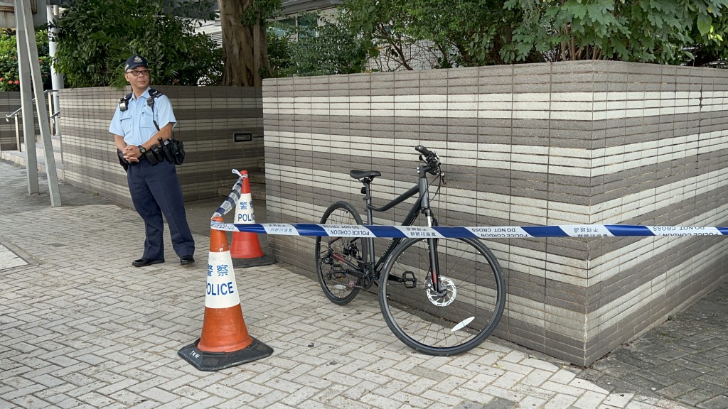 一部疑與案有關的單車泊在露明道行人路上，由警員看守。楊偉亨攝 