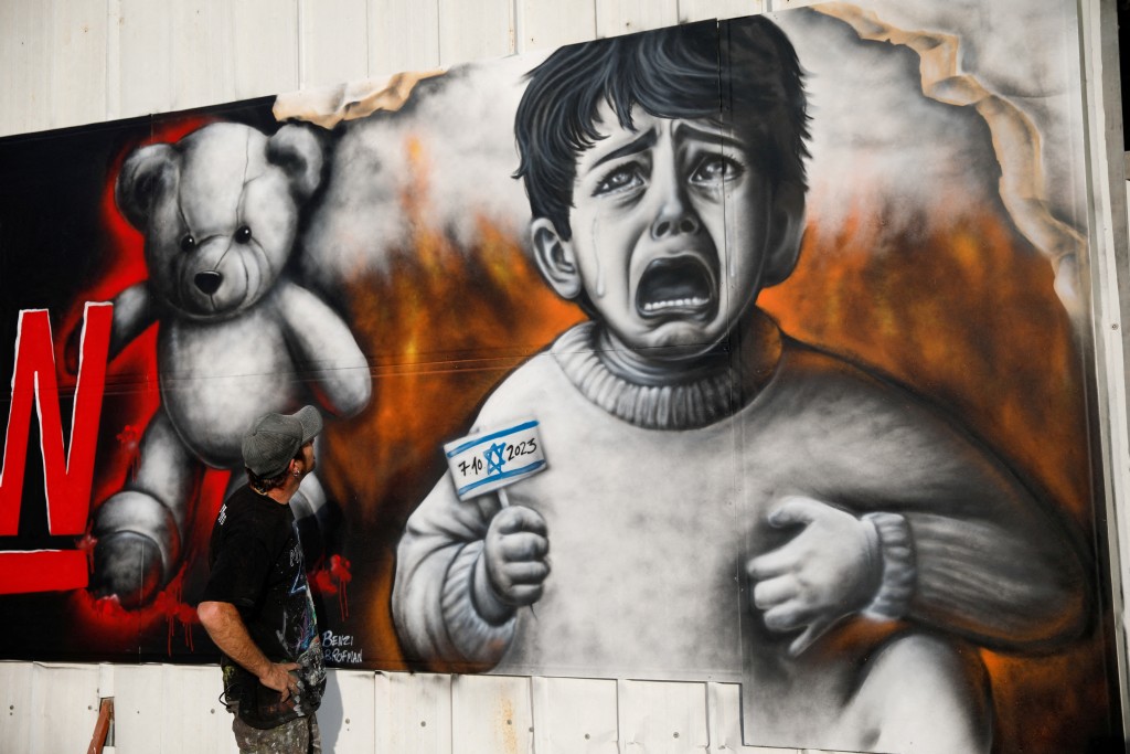以色列街头画家绘画小孩子哭喊海报，要求哈马斯尽快释放人质。路透社