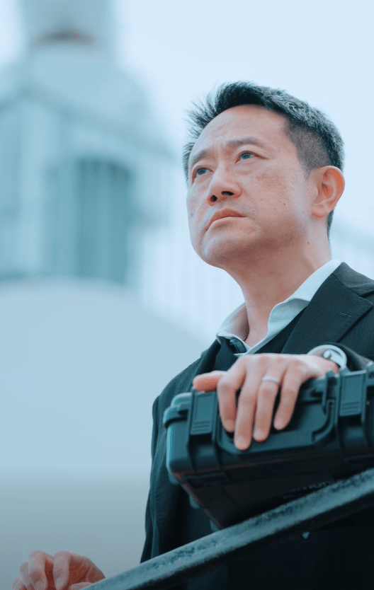 海關關長陳子達手持神秘行李箱，站在欄桿遠眺啟德郵輪碼頭的景色。海關FB影片截圖