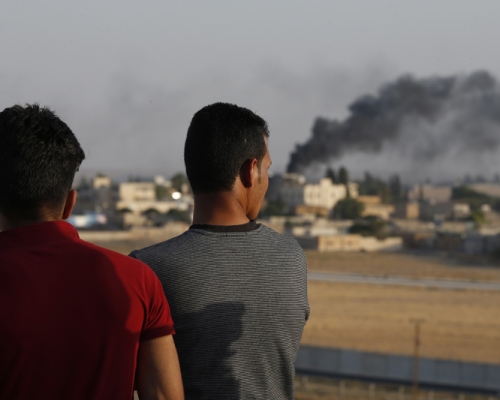 站在土耳其东南部Sanliurfa省Akcakale屋顶上的人民，在与叙利亚接壤的地方，看著土耳其轰炸叙利亚塔尔阿比亚德引起的大火。AP