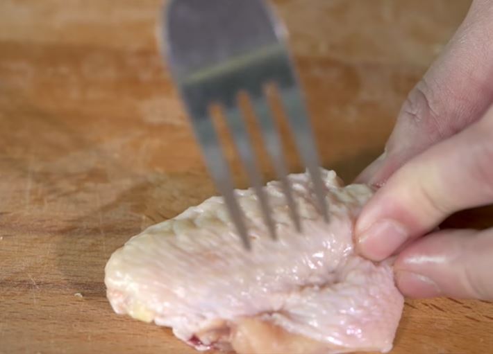 放醃料前，用叉把雞翼刺幾下可以令醃料更入味。（圖片來源：Youtube@Dishtravel）
