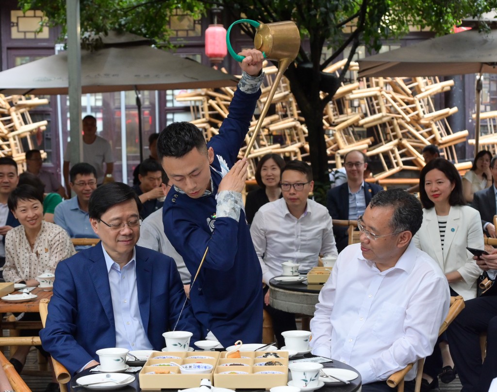 李家超（左）在四川省委常委、副省长普布顿珠（右）陪同下到访成都市人民公园了解当地饮食文化。政府新闻处图片