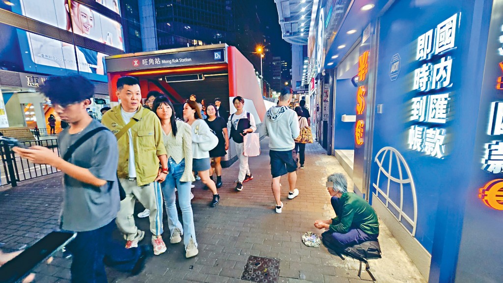 在旺角港鐵站出口外，一名中年婦女瑟縮街頭行乞。